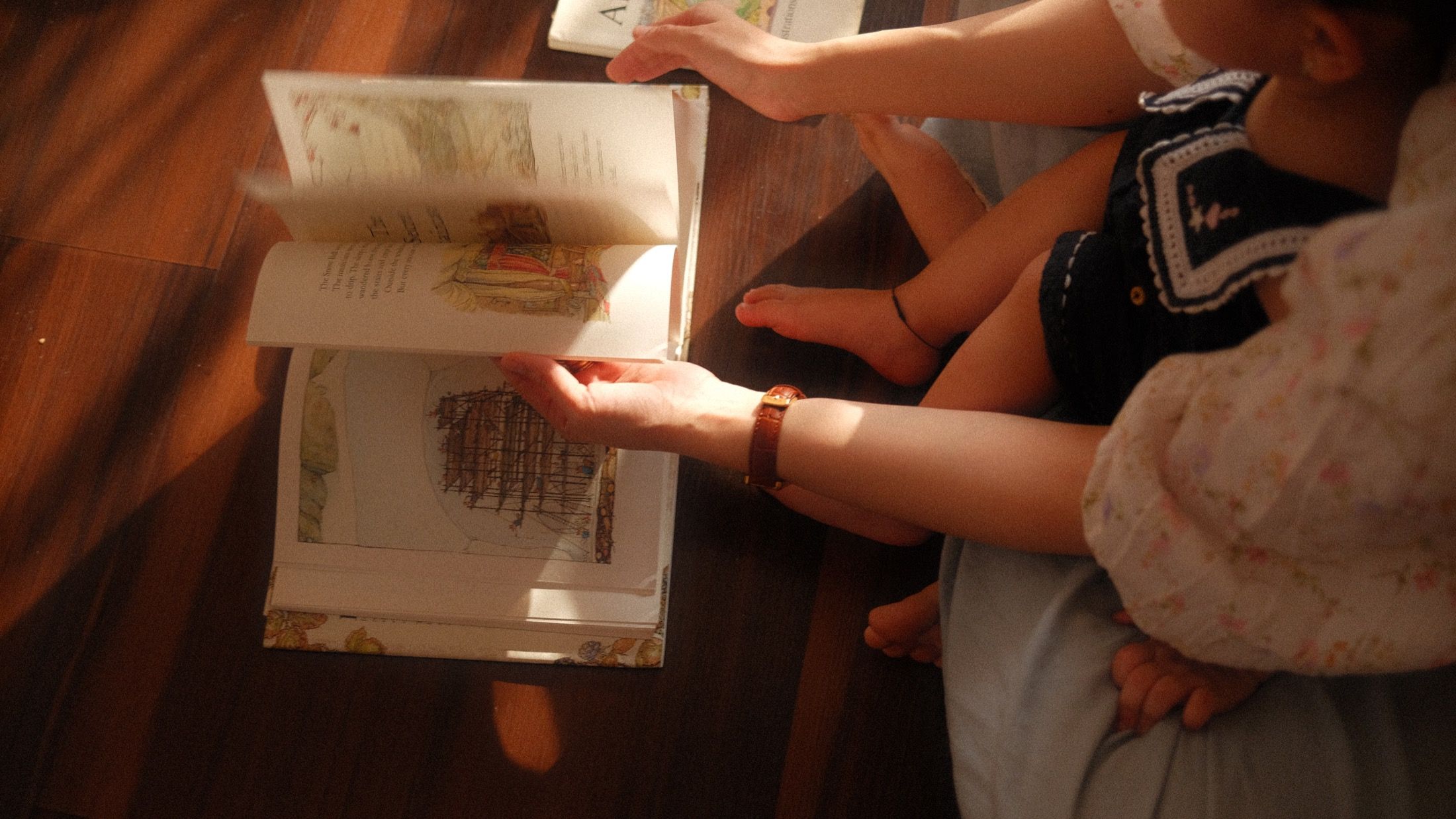 A shared story at home, with sunlight across the open book and children sitting close.